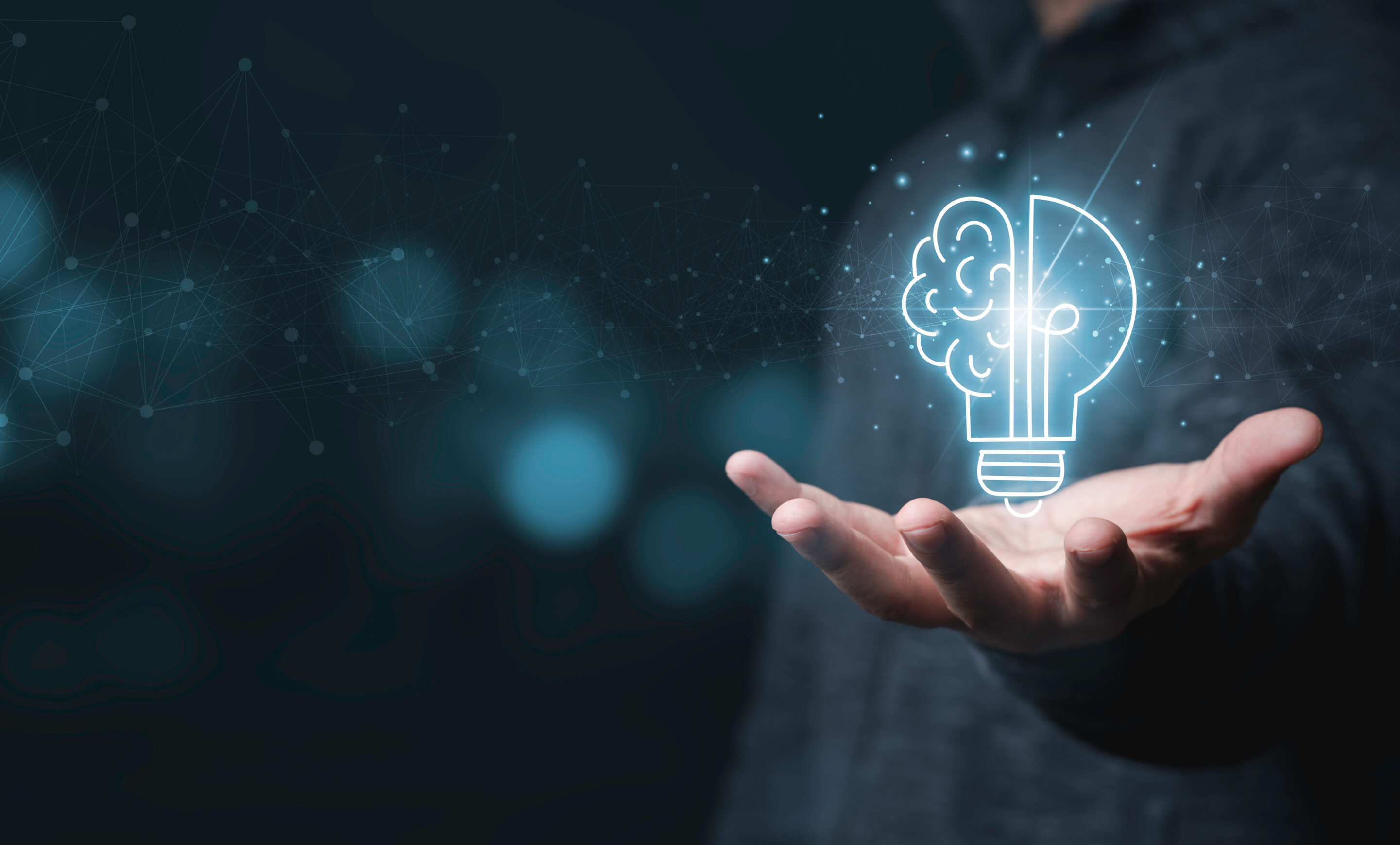 Businessman holding half of virtual lightbulb and brain on blue